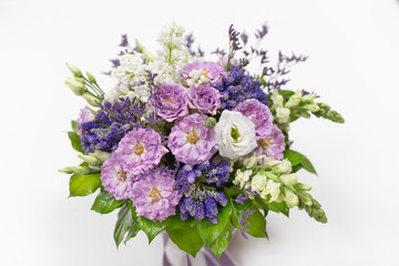 Exquisite bouquet of Roses, Eustoma, Veronica, Snapdragon and Lilac (white, lilac, green blue, lime, purple) in a small gift cardboard box on a light background