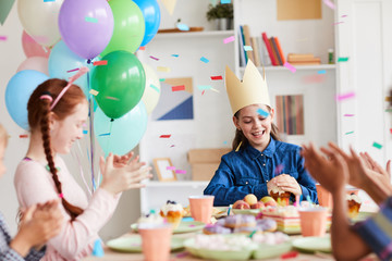 Group of happy children having fun while celebrating Birthday at party in decorated room with confetti, copy space