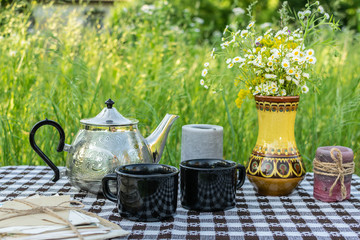 Hygge style summer composition with tea table in the garden.