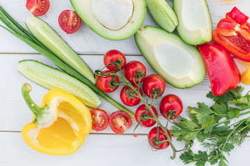 Fresh organic vegetables, cherry tomatoes, avocado, cucumbers, carrot, red and yellow pepper, green. Vegan food, healthy lifestyle concept
