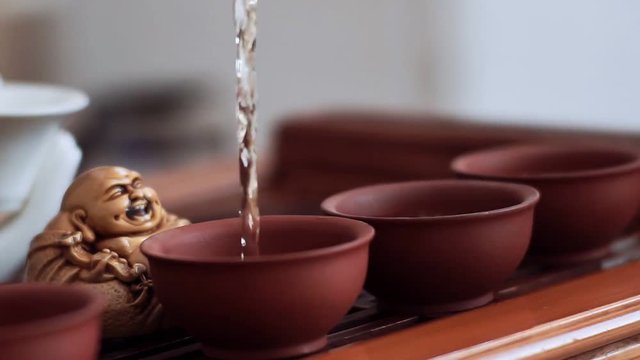 The girl skillfully and observing all the rules of the tea ceremony pours into small cups of tea