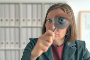 Businesswoman with magnifying glass doing business financial auditing