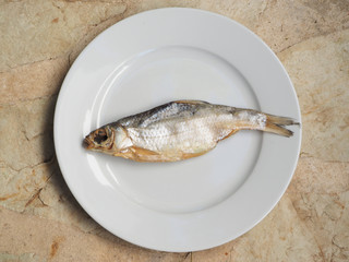 Salted dried fish on a plate top view.