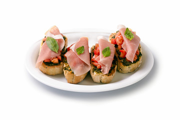 Bruschetta with tomato and ham on a plate, isolated on white background