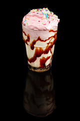Milk cocktail with ice cream, summer drink in glass, over black background