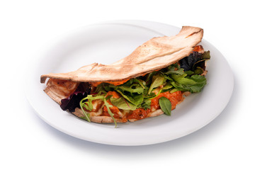 The concept of Italian cuisine, piadina with tomatoes, mozzarella cheese, mix lettuce, arugula and sauce on a plate, isolated on white background
