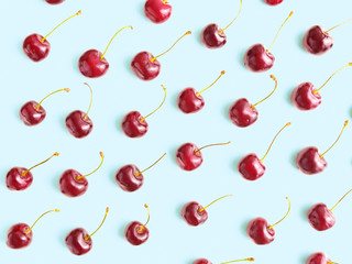 Ripe berries of sweet cherry are on a pale blue background. Flat lay, top view minimal composition.