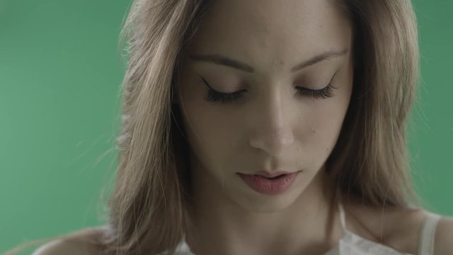 Attractive young woman with cat eye make up against green background