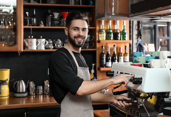 Barista with portafilter at coffee machine in shop