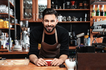 Portrait of barista with cup of coffee at bar counter