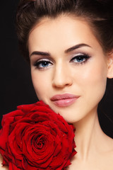Fototapeta na wymiar Portrait of young beautiful woman with winged eye makeup and red rose