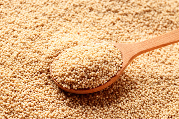 Wooden spoon with amaranth seeds on a amaranth background