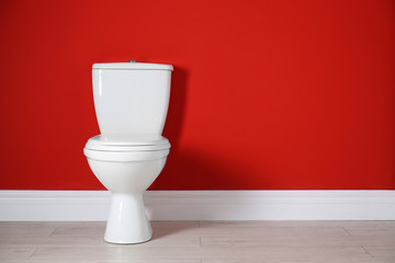 Toilet bowl near color wall in restroom. Space for text