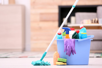 Bucket with cleaning supplies on floor indoors. Space for text