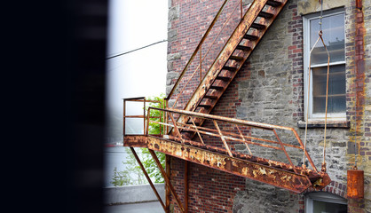 Old rusty fire escape stairs on brick building