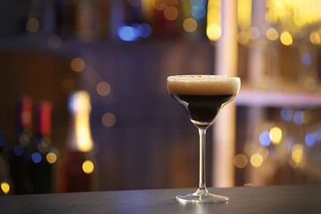 Glass of Espresso Martini on counter in bar, space for text. Alcohol cocktail