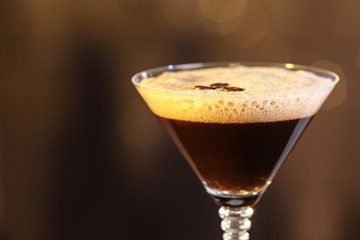 Glass of delicious Espresso Martini on blurred background. Alcohol cocktail