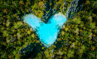Aerial top view of turquoise lagoon shaped heart inside of tropical island. Love travel summer...