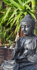 Statue of a meditating Buddha on a background of tropical greenery.