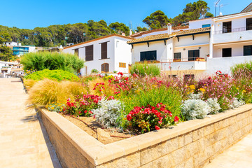 Coastal promenade with flowers and plants and typical white buildings in Sa Riera village, Costa Brava, Spain