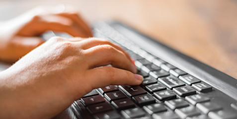 Woman working at home office hand on keyboard close up on wooden table background