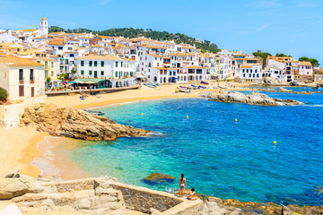 Couple of young woman in swimsuits on amazing beach in Calella de Palafrugell, scenic fishing village with white houses and sandy beach with clear blue water, Costa Brava, Catalonia, Spain