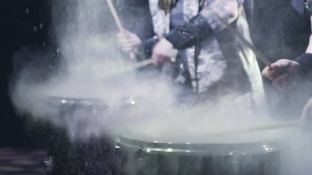Drummers banging sticks on drums. Action. Close-up of drummers banging sticks on big drums creating splash of white sprinkles on black background