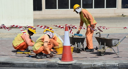 Bauarbeiter mit Helm und Sonnenschutz bei Straßenarbeiten in Abu Dhabi