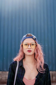 Millennial with Pink hair stands in front of bright blue wall