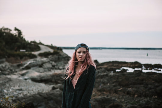 Stoic girl in early twenties stands on rocky east coast beach