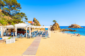 TOSSA DE MAR, SPAIN - JUN 3, 2019: People dining in restaurant on sandy beach in Tossa de Mar town, Costa Brava, Spain.