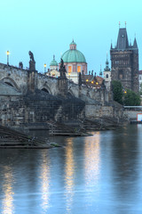 Fototapeta na wymiar View on eastern side of Charles Bridge with tower and dome of Clementinum in Prague, Czech Republic 