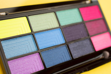 Colorful eyeshadow palette on yellow background