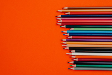 Color pencils on red-orange background.Close up.