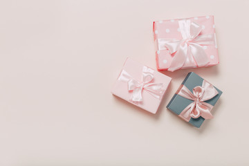 beautiful gift boxes wrapped in paper with gold and pink ribbon on a beige surface. Top view