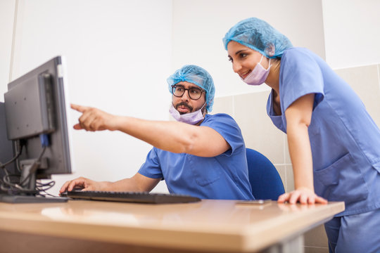 Team of surgeons, man and woman using the computer before the surgery and committing the details