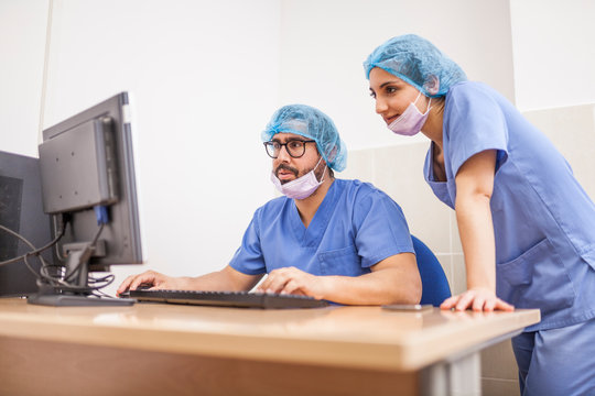 Team of surgeons, man and woman using the computer before the surgery and committing the details