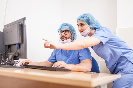 Team of surgeons, man and woman using the computer before the surgery and committing the details