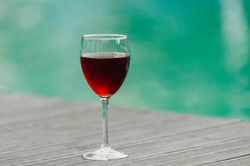 Red wine in a glass on water swimpool background