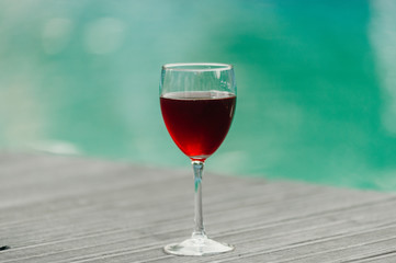 Red wine in a glass on water swimpool background