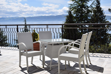 White table with chairs on a terrace near the sea.