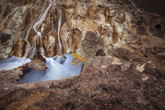 Small stream flowing on sandy rock on sunny day in long exposure in Mines of Riotinto, Huelva