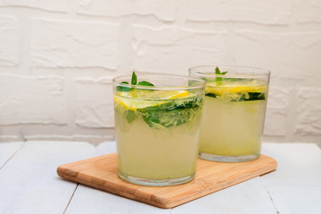 Two glasses of Sassy Water on wooden board on white background with copy space