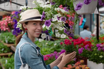 Foto op Canvas  Young woman shopping in an outdoors fresh urban flowers market, buying and picking from a large variety of colorful floral bouquets during a sunny day in the city © artursfoto