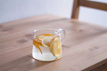 pitcher with lemonade and water sliced oranges and lemon on wooden table and coral and blue table background close up with blurred background
