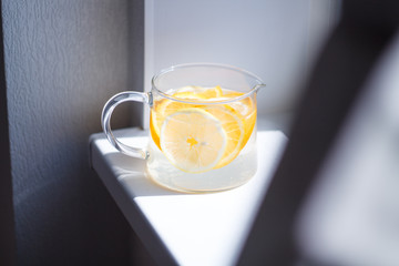 pitcher with lemonade and water sliced oranges and lemon on white table close-up with blurred background