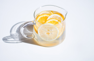 pitcher with lemonade and water sliced oranges and lemon on white table close-up with blurred background
