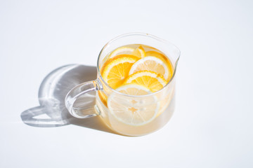 pitcher with lemonade and water sliced oranges and lemon on white table close-up with blurred background