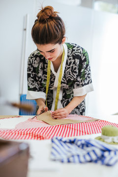 Teenage girl student practicing sewing on modern machine in cozy workshop