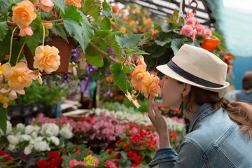 Foto op Canvas  Young woman shopping in an outdoors fresh urban flowers market, buying and picking from a large variety of colorful floral bouquets during a sunny day in the city © artursfoto